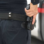 Person holding a gun in a holster.