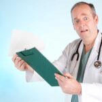 A doctor in a white coat looking surprised while holding a clipboard