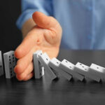 Trump Freezes Immigration—Security Threat Exposed Hand stopping falling row of dominoes.