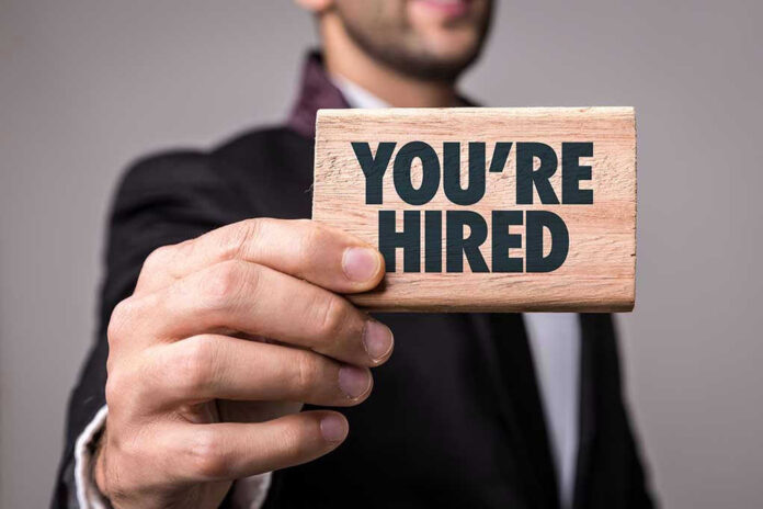623590175 Person holding a Youre Hired sign.