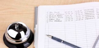 A reception desk with a bell, a pen, and a guest logbook