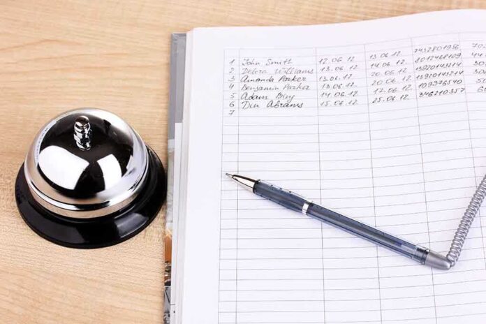 A reception desk with a bell, a pen, and a guest logbook
