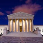 The Supreme Court building illuminated at night with a clear sky