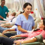 A nurse smiling at a female donor during a blood donation session