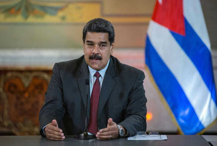 Man speaking at podium with Cuban flag in background.