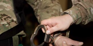 A military personnel placing handcuffs on an individual