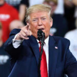 Trump Drops Endorsement Hammer Over Election Bill Man in suit pointing, speaking at a rally.