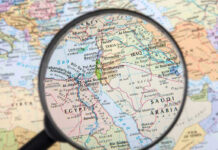 Magnifying glass over Middle East map highlighting Israel and Egypt.