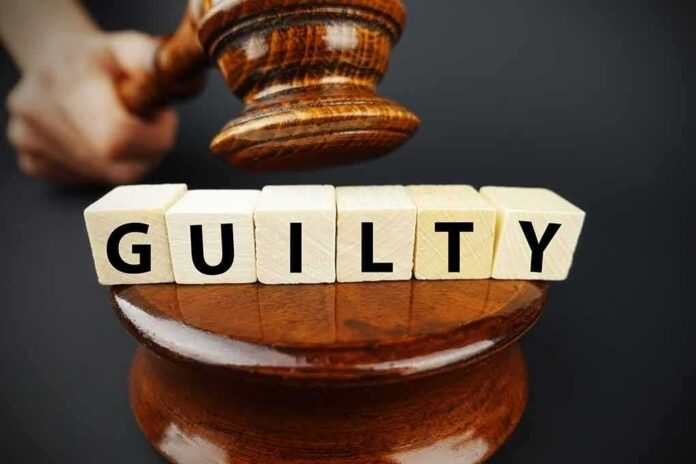 A gavel striking down next to wooden blocks spelling 'GUILTY'