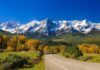 Scenic view of snow-capped mountains with autumn trees and a winding road