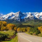Historic Route 66: The Ultimate Centennial Party Scenic view of snow-capped mountains with autumn trees and a winding road