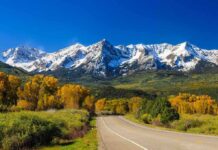 Historic Route 66: The Ultimate Centennial Party Scenic view of snow-capped mountains with autumn trees and a winding road