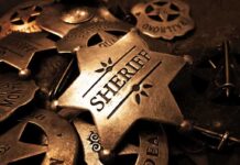 A collection of vintage sheriff badges arranged on a dark surface