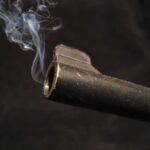 White House Dinner Plot: Long Gun Horror Close-up of a gun barrel emitting smoke against a black background