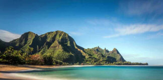 Beach with mountains and clear blue water.