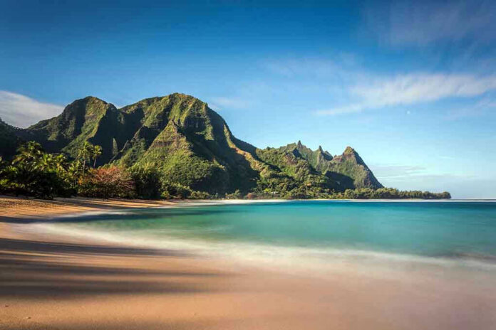 Beach with mountains and clear blue water.