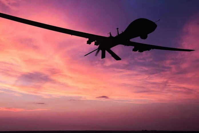 Silhouette of a drone against a colorful sunset.
