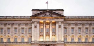 Front view of Buckingham Palace with illuminated facade and British flag