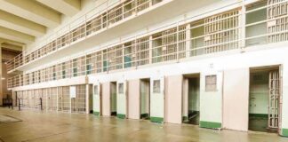Interior view of a prison cell block with empty cells and security bars