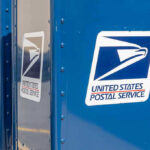 Blue USPS mail collection boxes in a row.