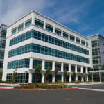 Modern office building with glass windows, clear sky.