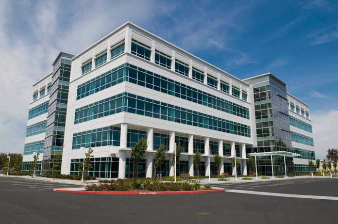 32039629 Modern office building with glass windows, clear sky.