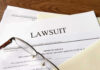 Documents labeled Lawsuit with glasses on top.