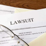 Documents labeled Lawsuit with glasses on top.