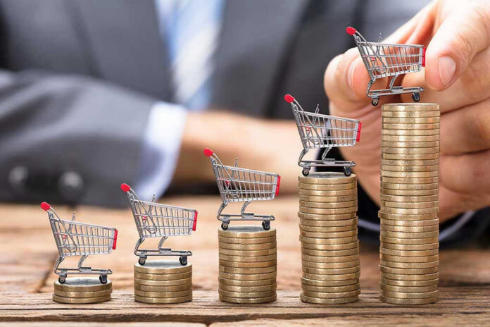Mini shopping carts on stacks of coins, business background.
