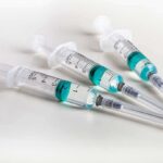 Three syringes filled with blue-green liquid on a white surface