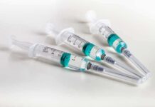 Three syringes filled with blue-green liquid on a white surface