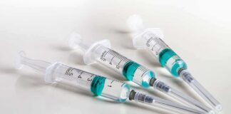 Three syringes filled with blue-green liquid on a white surface