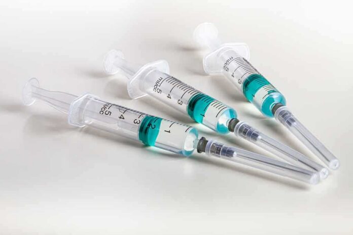 Three syringes filled with blue-green liquid on a white surface