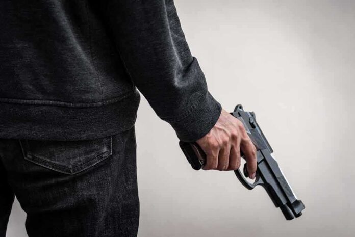person holding a handgun at their side