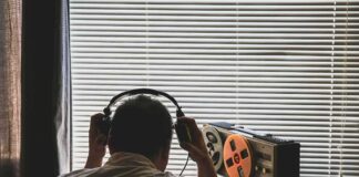 Person wearing headphones listening to a reel-to-reel tape recorder