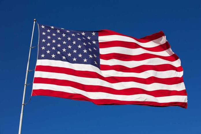 Rippled,Us,Flag,On,A,Windy,Day Waving American flag against a clear blue sky
