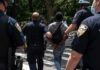Police escort a handcuffed man across a city street