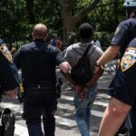 Police escort a handcuffed man across a city street