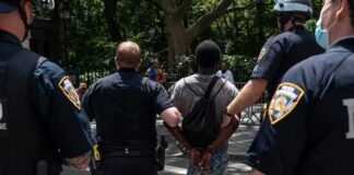 Police escort a handcuffed man across a city street