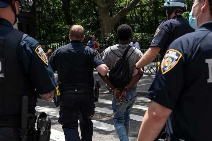 Police escort a handcuffed man across a city street