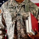 A soldier in a U.S. Army uniform holding books in front of an American flag