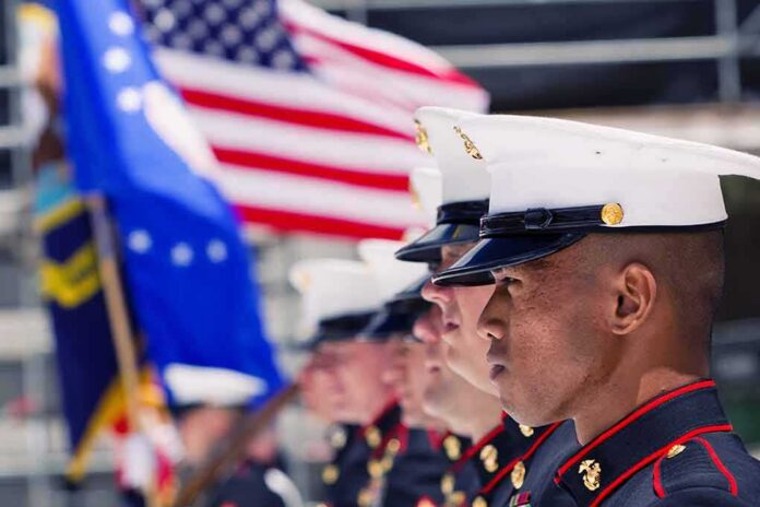 U.S. Marines in uniform standing in formation with flags in the background