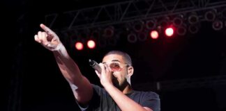 Musician performing on stage with a microphone and pointing to the audience