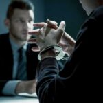 Handcuffed person in interview with suited man