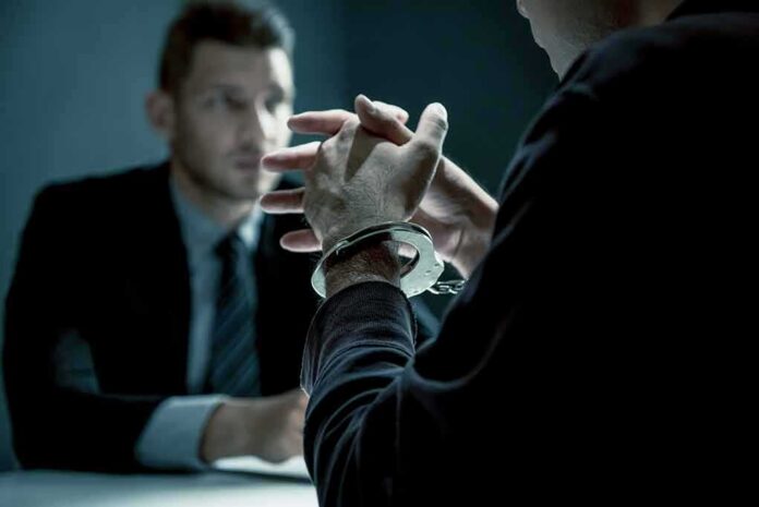 Handcuffed person in interview with suited man