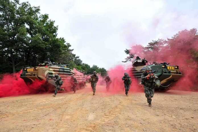 Soldiers running with armored vehicles through red smoke