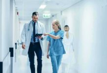 Doctors walking in a hospital corridor reviewing a tablet
