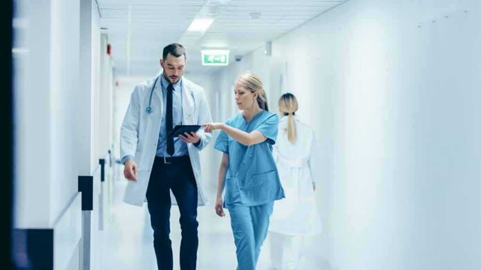 Doctors walking in a hospital corridor reviewing a tablet