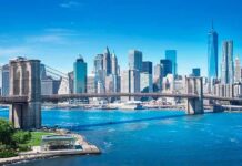 Brooklyn Bridge spanning blue river with modern city skyline