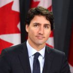 Canada Strikes Back — 50% Pain man in suit at podium with Canadian flags